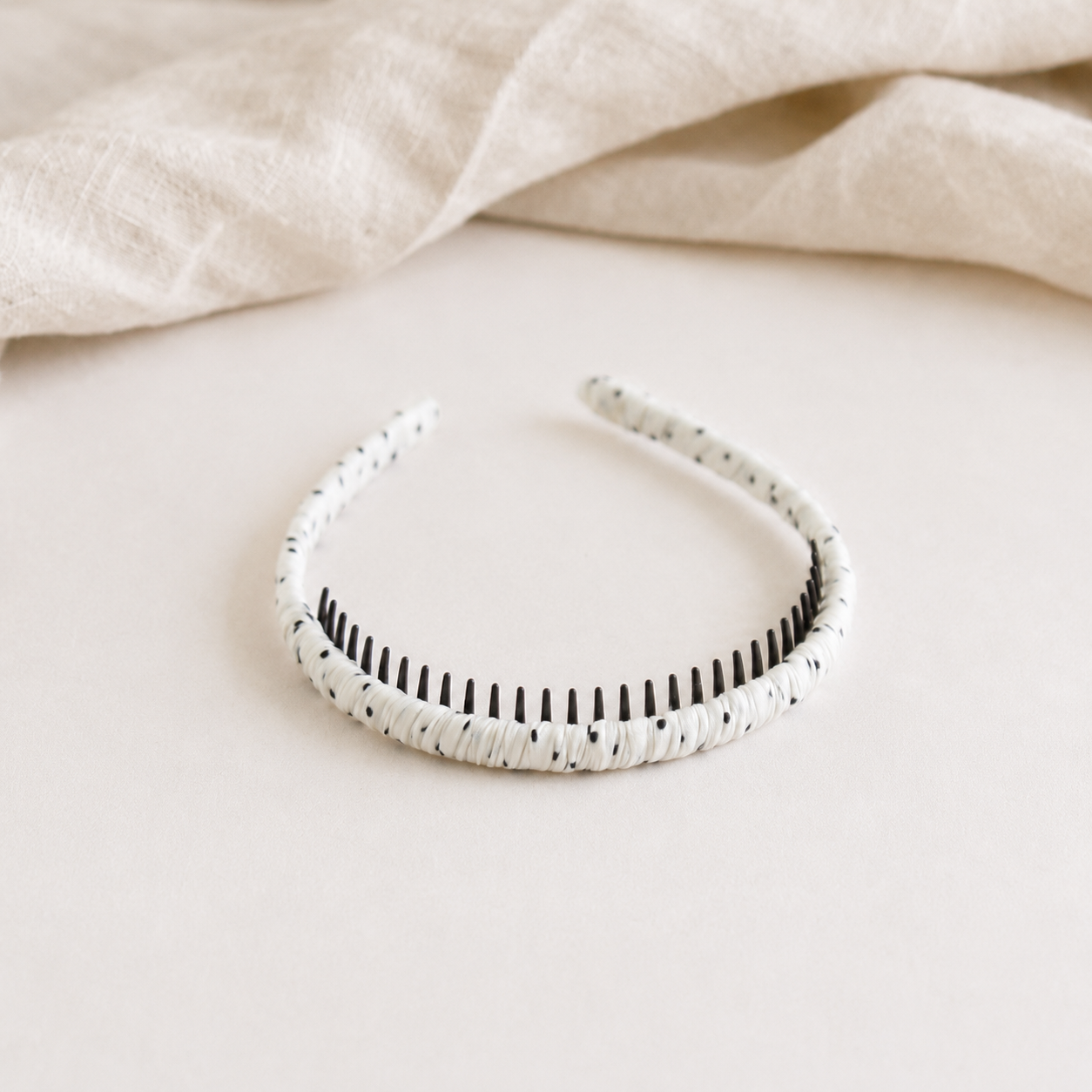 White headband with black pattern on a beige fabric background