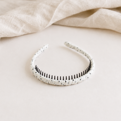 White headband with black pattern on a beige fabric background